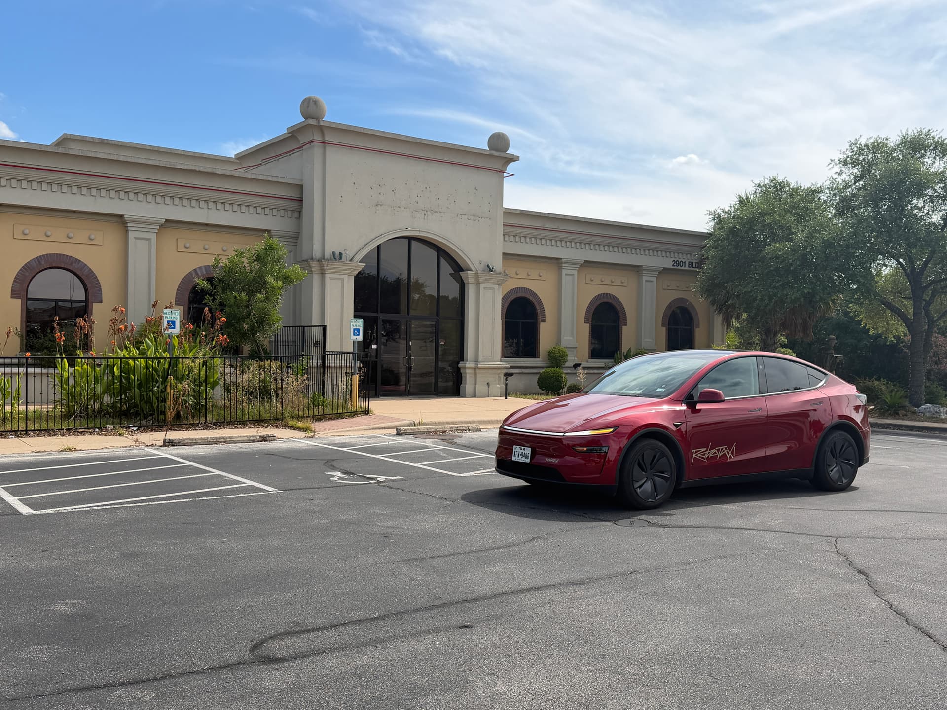 A red Tesla Robotaxi parked outside a building in Austin, Texas